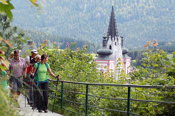 Wanderer auf einem Wanderweg unterwegs und im Hintergrund befindet sich die Basilika Mariazell